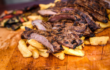 Sliced grilled juicy marinated beef flank steak on wooden board.