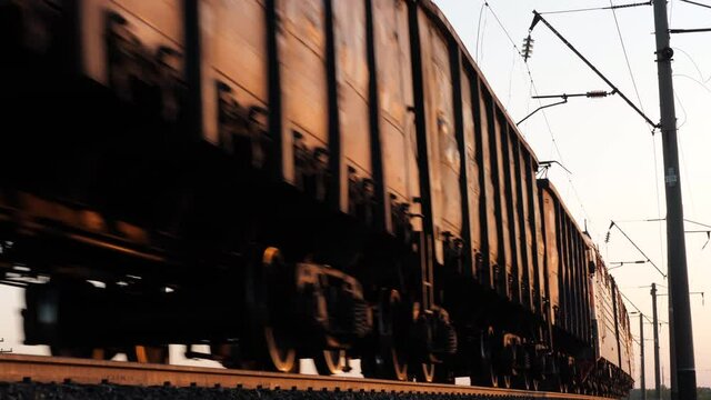 Freight train moves, carry wagons row, import or export of goods containers at sunset. Business logistics as railway commercial merchandise shipping, intermodal trucking industry. Cargo transportation