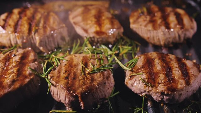 Delicious juicy meat steak cooking on grill. Aged prime rare roast grilling tenderloin fresh marble tenderness beef. Prime beef fry on electric roaster, rosemary, black pepper, salt. Slow motion.