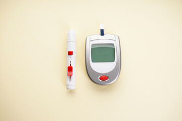 Digital glucometer and lancet pen on yellow background, close-up, flat lay. Diabetes concept. Blood...
