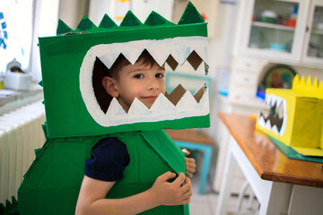 Smiling boy wearing a cardboard dinosaur costume	
