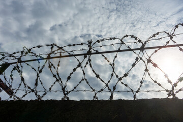 barbed wire against the sky, in dark colors, the concept of a closed border