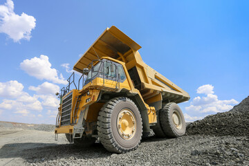 Quarry dump truck, in open pit. Work in quarry stone. Blue sky background