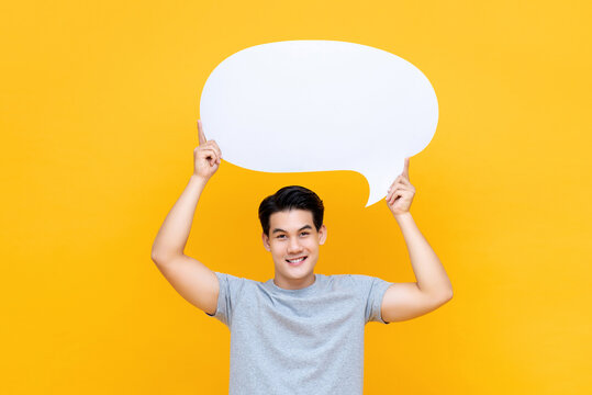 Smiling handsome Asian man holding speech bubble overhead