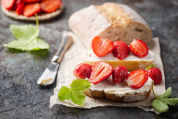 Strawberries sandwiches with cream cheese and on paper, gray background