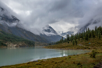 Akkem Lake at the foot of Belukha Mountain in Altai. Reflection of the mountain in the water. Low cloud cover.
