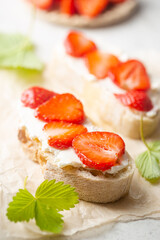 Strawberries sandwiches with cream cheese and on paper, light background