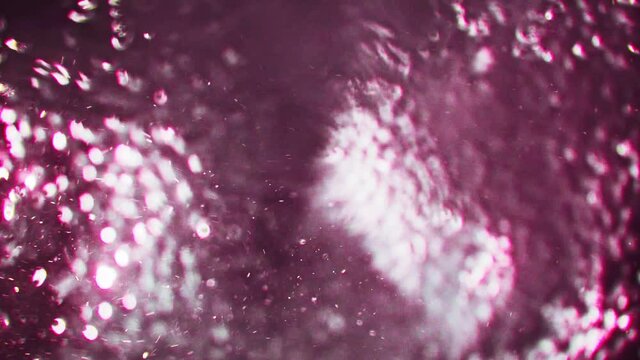 Video of underwater colorful bubbles rising to surface in slow motion 180fps. Close up, refreshing soda tonic fizzy water, bubbles dissolve in mineral carbonated drink. Bubbles particles rise up.