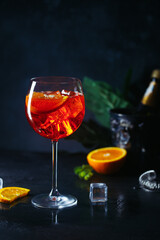 Aperol spritz cocktail in glass with fresh orange on dark background