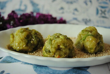 Vegan Green Bean Balls, places in Sesame seeds in a white plate, on an old tiles background.