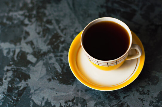 One yellow vintage cup with tea or coffee on a dark background