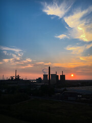 Scenic view of power station and cooling tower at sunset against sky.