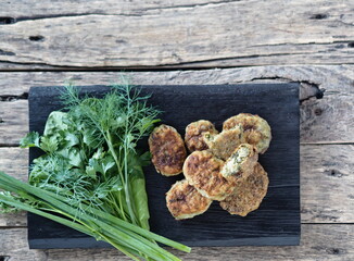 Healthy vegetarian and dietary food. Vegetable and fish cutlets with greens on a wooden background.