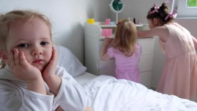 three daughters play with makeup in the parents bedroom