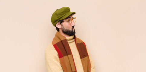 young cool bearded man looking puzzled and confused, biting lip with a nervous gesture, not knowing...