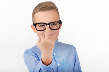 Attractive young caucasian schoolboy with glasses an blue shirt shows middle finger.Close up concept.Studio white wall.