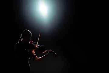 Tuinposter silhouette of female musician playing on violin on dark stage with back light © LIGHTFIELD STUDIOS