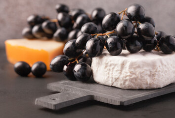 Black grapes with soft French cheese on the Board as an appetizer for wine