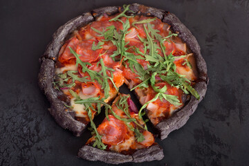 Round pizza on a thin dough with rucola, red tomatoes, cheese and ham