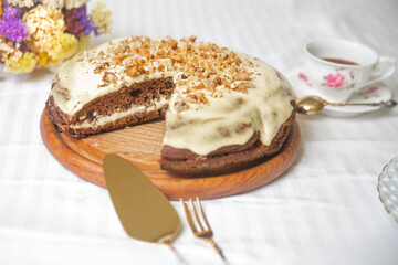 Carrot cake on the white textile material, with flowers and a cup of coffee.