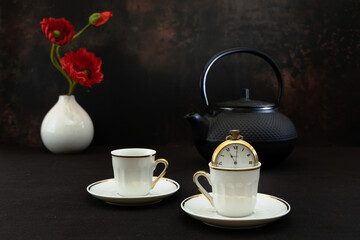 a still life set up using a Japanese tetsubin, white china cups and poppies, shot against a dark background
