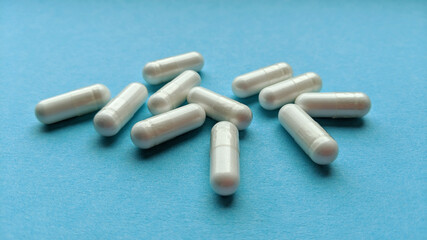 White pill capsules on blue background. Simple flat lay with pastel texture. Medical concept. Stock photo.