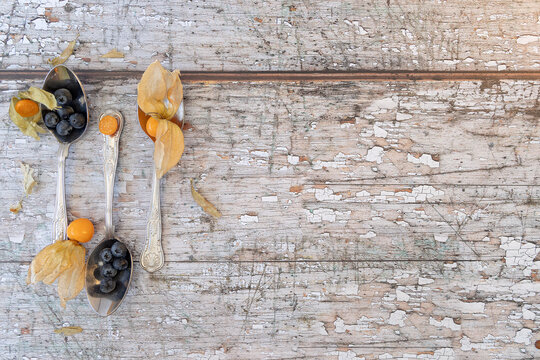 three teaspoons shot from above with physalis and blueberries, shot on a textured wooden background