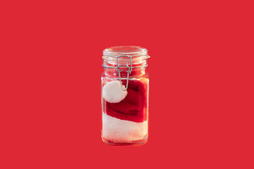 Santa hat in a glass container on a red background