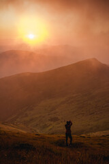 Fototapeta premium girl photographs the sunset in the mountains
