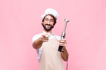 young crazy cool man with a hand blender against pink wall