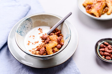 Healthy breakfast yogurt bowl with granola and caramelized bananas and nuts on grey concrete background. Selective focus