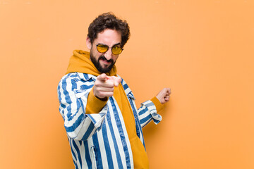 young crazy cool man pointing to the side against orange wall