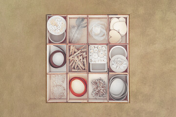 Wooden box with 12 compartments full of things shot against textured background