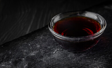 Soy sauce in small glass dish black background