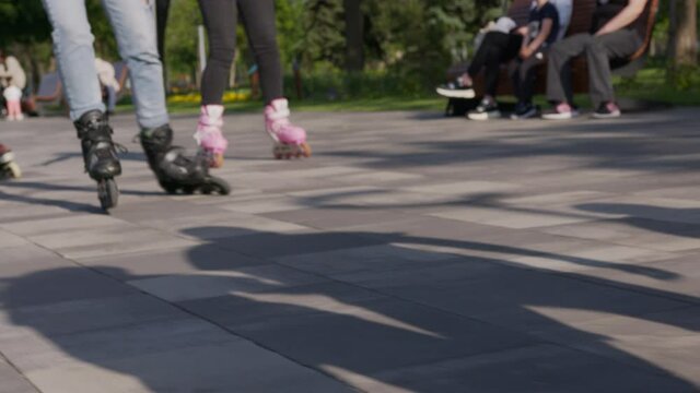 Close-up legs of teenagers. Riding roller skating down the street.