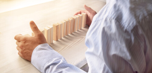 Young man with wooden cubes on the desktop in the office as a concept.