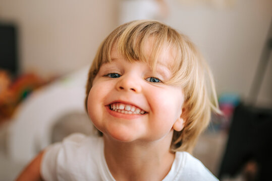 little blond boy laughs looking at camera at home. fun at home family at home