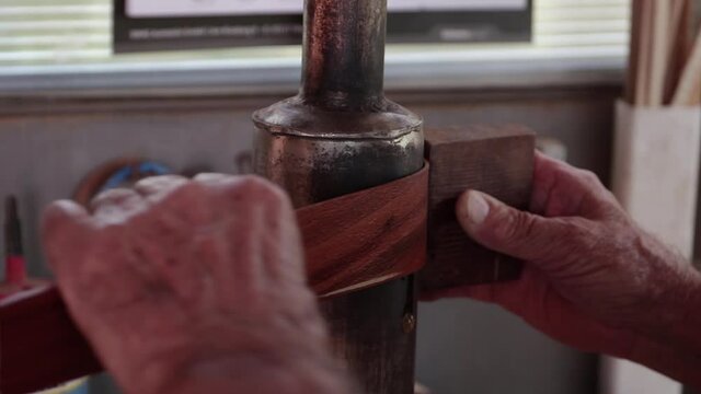 Guitar maker moulding wood trim for classical guitar body on heating element. Handheld. Close up