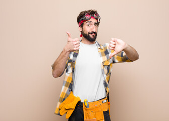 young housekeeper man feeling confused, clueless and unsure, weighting the good and bad in...