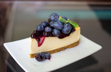 Blueberry cheesecake on squared white plate on glass table