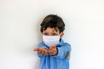 Boy wearing anti virus mask staying at home.Shot of boy with opened hands isolated on white backgrounds.Young boy looking at camera,holding hands open,wearing protective mask protection from COVID-19.