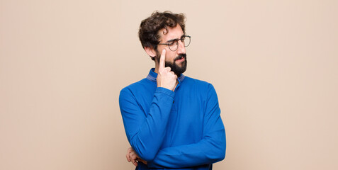 young handsome man with a concentrated look, wondering with a doubtful expression, looking up and...