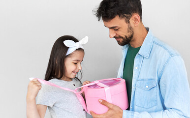 Fototapeta premium ?ute daughter giving to the dad a gift box on holiday for Father's day. Pretty little girl receives a present from her father. Daddy and his child enjoy time together, share the love.