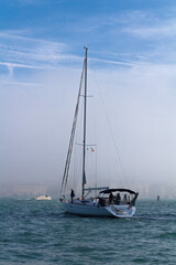 Fototapeta premium Sailing yacht enters the foggy harbor.