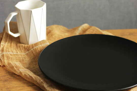 Empty black plate and white cup. Empty dishes. Minimalistic set of dishes. Plate without food