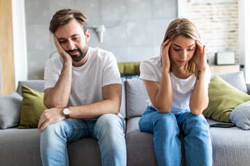 Portrait of couple are sitting on couch and are quarreling with each other.