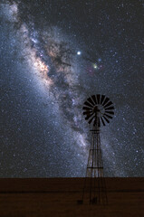 Wiatrak na farmie i nocne niebo gwiezdziste z centrum Drogi Mlecznej w bezksiężycową noc