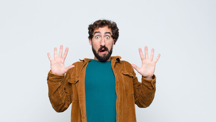 young handsome man feeling stupefied and scared, fearing something frightening, with hands open up...