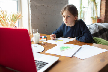 Girl drawing with paints and pencils at home, watching teacher's online tutorial on laptop. Digitalization, remote education concept. Technologies, devices. Man showing, giving online lesson. Artwork.