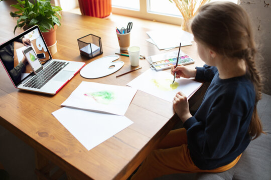 Girl drawing with paints and pencils at home, watching teacher's online tutorial on laptop. Digitalization, remote education concept. Technologies, devices. Man showing, giving online lesson. Artwork.